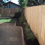New fencing outlines the rear yard. A mow strip of brick defines the planter beds, utility area and the rear lawn area.